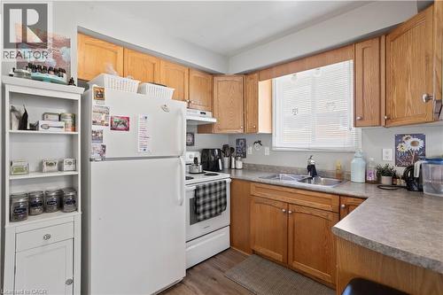 Kitchen featuring wood-finish cabinetry, a double basin stainless steel sink, and light-toned countertops - 179 Vancouver Street, London, ON - Indoor Photo Showing Kitchen With Double Sink