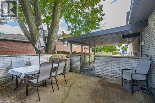 Concrete patio featuring a partial overhead covering, white brick half-wall, and a mature tree providing natural shade - 179 Vancouver Street, London, ON - Outdoor With Deck Patio Veranda With Exterior