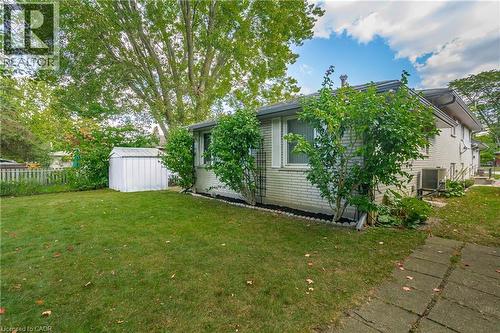 Expansive side yard featuring a manicured lawn, established mature trees, and a white storage shed - 179 Vancouver Street, London, ON - Outdoor