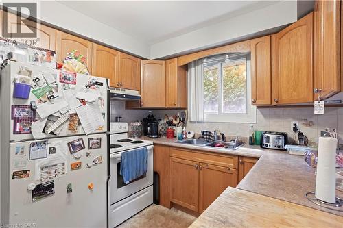 Kitchen featuring wood-finish cabinetry, a double-basin stainless steel sink, and a window above the sink - 179 Vancouver Street, London, ON - Indoor Photo Showing Kitchen With Double Sink