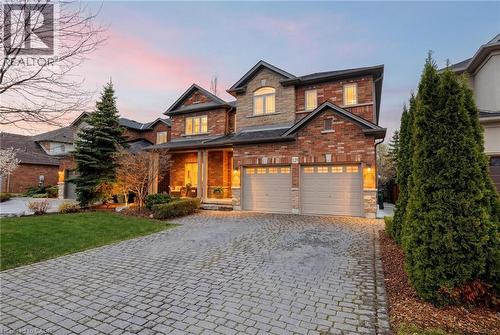 Brick and stone facade residence featuring a two-car garage, covered entry porch, and a patterned paver driveway - 129 Magnificent Way, Binbrook, ON - Outdoor