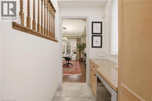 Hallway featuring tile flooring, a built-in desk area with light wood cabinetry, a window with blinds, and a wooden staircase railing - 129 Magnificent Way, Binbrook, ON - Indoor Photo Showing Other Room