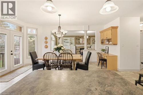 Dining area featuring a chandelier, French doors leading to an exterior deck, and an integrated desk with upper cabinetry - 129 Magnificent Way, Binbrook, ON - Indoor Photo Showing Dining Room