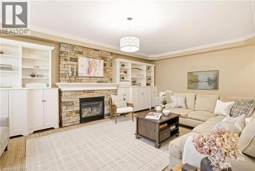 Stone-clad fireplace with mantel and gas insert, flanked by built-in white cabinetry with open shelving - 129 Magnificent Way, Binbrook, ON - Indoor Photo Showing Living Room With Fireplace