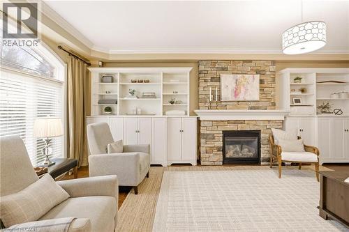 Stacked stone fireplace with a white mantel, flanked by built-in white cabinetry and shelving - 129 Magnificent Way, Binbrook, ON - Indoor Photo Showing Living Room With Fireplace