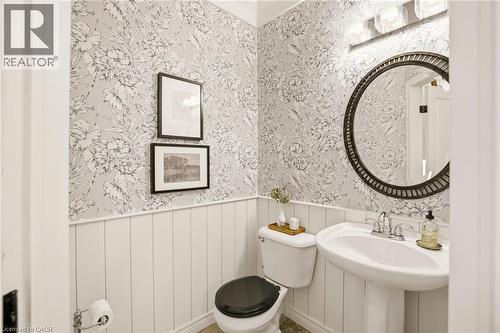 Pedestal sink with chrome faucet, complemented by a round framed mirror above - 129 Magnificent Way, Binbrook, ON - Indoor Photo Showing Bathroom