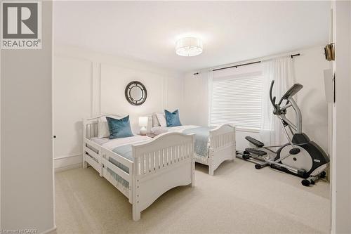 Carpeted room featuring a white ceiling light fixture, window with horizontal blinds, and wall panel molding - 129 Magnificent Way, Binbrook, ON - Indoor Photo Showing Bedroom