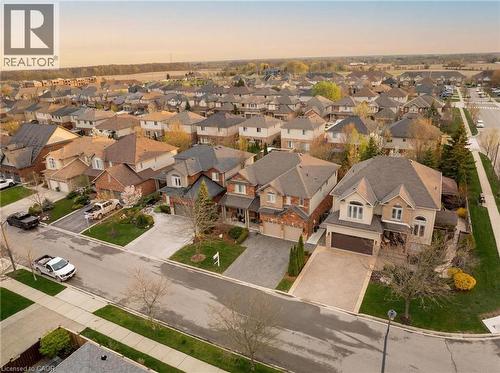 Residential street featuring two-story homes with brick and stucco exteriors, attached garages, and paved driveways - 129 Magnificent Way, Binbrook, ON - Outdoor With View
