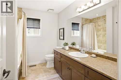 Bathroom with a brown wood-finish vanity, integrated sink, and an expansive mirror - 129 Magnificent Way, Binbrook, ON - Indoor Photo Showing Bathroom