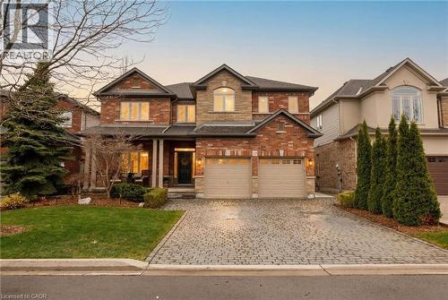 Brick and stone facade residence featuring a covered front porch, a two-car garage, and a paver driveway - 129 Magnificent Way, Binbrook, ON - Outdoor With Facade