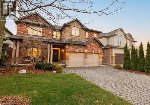Two-story brick and stone facade residence featuring a covered front porch, two-car garage, and a paver stone driveway - 129 Magnificent Way, Binbrook, ON - Outdoor With Facade