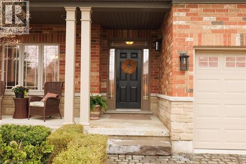 Brick and stone facade featuring a recessed entry, covered porch with square columns, and a paneled garage door with upper window inserts - 129 Magnificent Way, Binbrook, ON - Outdoor With Exterior
