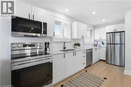 Kitchen featuring white shaker-style cabinetry, stainless steel appliances, light-toned wood-finish flooring, white subway tile backsplash, and recessed lighting - 11 Marcella Crescent, Hamilton, ON - Indoor Photo Showing Kitchen With Stainless Steel Kitchen With Double Sink With Upgraded Kitchen