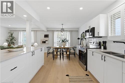 Contemporary kitchen featuring white cabinetry, light-toned countertops, stainless steel appliances, and wood-finish flooring - 11 Marcella Crescent, Hamilton, ON - Indoor Photo Showing Kitchen With Double Sink With Upgraded Kitchen