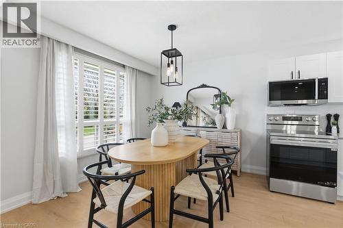 Dining area featuring a wood-finish flooring, a contemporary chandelier, and a window with plantation shutters and drapes - 11 Marcella Crescent, Hamilton, ON - Indoor Photo Showing Other Room