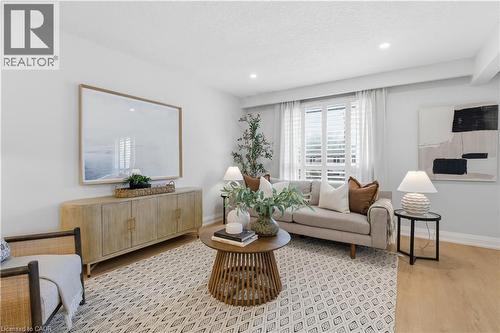 Bright living area featuring light wood-finish flooring, recessed lighting, and a window with plantation shutters - 11 Marcella Crescent, Hamilton, ON - Indoor Photo Showing Living Room