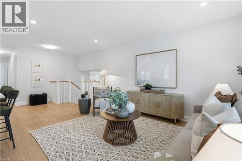 Open concept living area featuring light wood-finish flooring, recessed lighting, white walls, and a staircase with white balusters - 11 Marcella Crescent, Hamilton, ON - Indoor