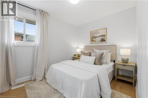 Bright bedroom featuring light-toned walls, wood-finish flooring, and a single window with white trim - 11 Marcella Crescent, Hamilton, ON - Indoor Photo Showing Bedroom
