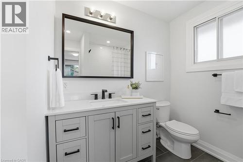 Bathroom featuring a light gray vanity with black hardware, white countertop, and black-framed mirror - 11 Marcella Crescent, Hamilton, ON - Indoor Photo Showing Bathroom
