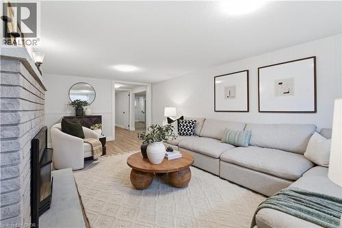 Spacious living area featuring a brick fireplace, light wood-finish flooring, recessed lighting, and a neutral color palette - 11 Marcella Crescent, Hamilton, ON - Indoor Photo Showing Living Room
