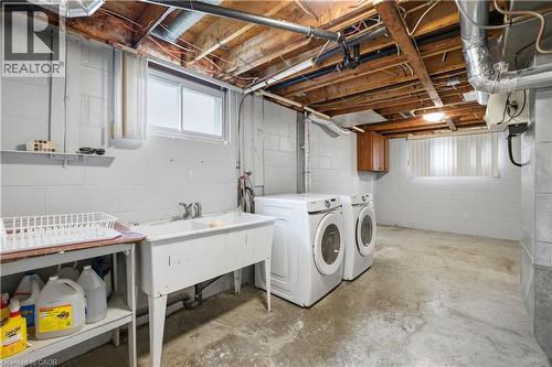 Utility room featuring concrete block walls, exposed wood ceiling joists, and a double basin utility sink - 11 Marcella Crescent, Hamilton, ON - Indoor Photo Showing Laundry Room