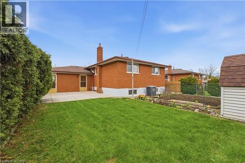 Expansive rear yard featuring a verdant lawn, a concrete patio, and a dedicated garden bed - 11 Marcella Crescent, Hamilton, ON - Outdoor With Exterior