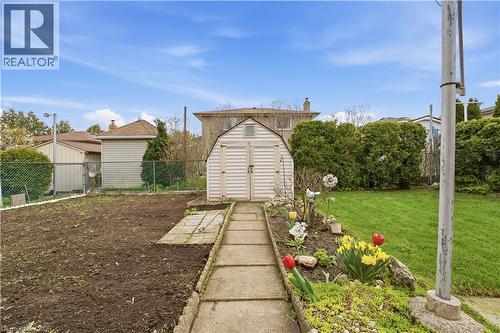 Backyard featuring a concrete pathway, a storage shed, a garden bed with plantings, and a chain-link fence - 11 Marcella Crescent, Hamilton, ON - Outdoor