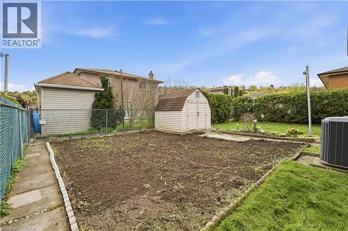 Spacious backyard area featuring a detached storage shed, chain-link fencing, and a concrete pathway - 11 Marcella Crescent, Hamilton, ON - Outdoor