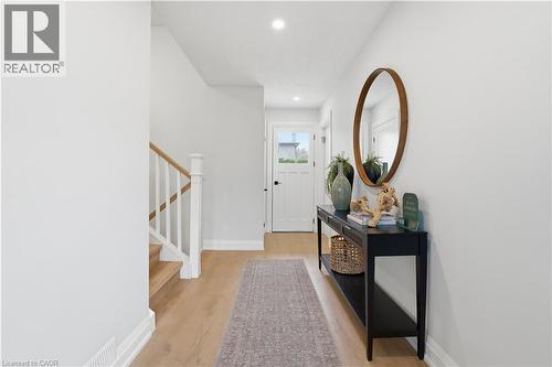 Entryway featuring wood-finish flooring, white walls, recessed lighting, and a partial staircase with white balusters and a light wood handrail - 11 Marcella Crescent, Hamilton, ON - Indoor Photo Showing Other Room
