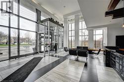 Spacious entryway featuring a full-height glass wall, high ceilings, a built-in reception desk with a dark countertop, and a modern light-toned flooring pattern - 