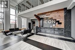 Two-story lobby featuring a wood-finish accent wall, dark stone wall paneling, and a geometric-patterned reception desk - 