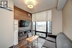 Living space featuring expansive window, wood-finish accent wall, and wood-finish flooring - 