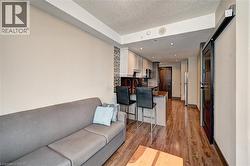 Open-concept living space featuring wood-finish flooring, recessed lighting, and a modern kitchen with stainless steel appliances - 