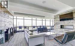 Spacious lounge area featuring a floor-to-ceiling window wall, a linear fireplace set into a stone accent wall, an integrated bar area with dark cabinetry, and recessed ceiling lighting - 