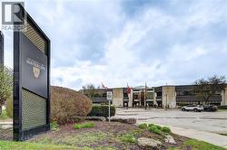 Prominent University of Waterloo signage, mature landscaping, and a multi-story institutional building with a spacious paved parking area - 