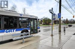 Curbside bus stop featuring a metal bench, a bus shelter pole with signage, and a public transit bus - 