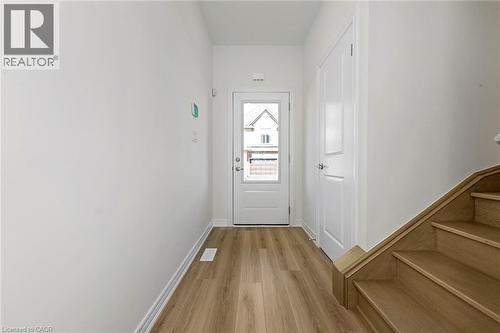 Entryway featuring wood-finish flooring, white baseboards, a white paneled door, and a wooden staircase - 205 Thames Way Unit# 31, Hamilton, ON - Indoor Photo Showing Other Room