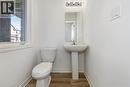 Pedestal sink with mirror and vanity lighting, white toilet, wood-finish flooring, and a window with white trim - 205 Thames Way Unit# 31, Hamilton, ON  - Indoor Photo Showing Bathroom 