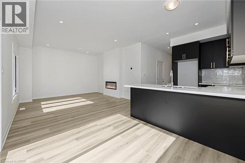 Open-concept living space featuring wood-finish flooring, recessed lighting, and a modern linear fireplace - 205 Thames Way Unit# 31, Hamilton, ON - Indoor Photo Showing Kitchen