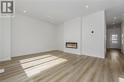 Open concept living space featuring a built-in linear electric fireplace, recessed lighting, wood-finish flooring, and white baseboards - 205 Thames Way Unit# 31, Hamilton, ON - Indoor With Fireplace