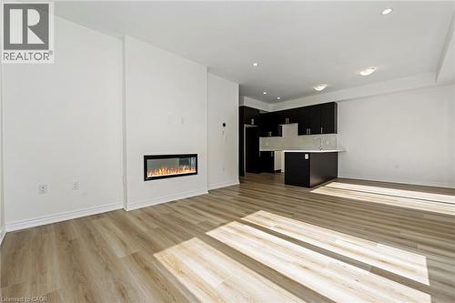 Open-concept living area with wood-finish flooring, a linear electric fireplace, and recessed lighting - 205 Thames Way Unit# 31, Hamilton, ON - Indoor Photo Showing Living Room With Fireplace