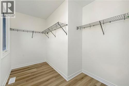 Walk-in closet with wire shelving system, wood-finish flooring, white baseboards, and a window for natural light - 205 Thames Way Unit# 31, Hamilton, ON - Indoor With Storage