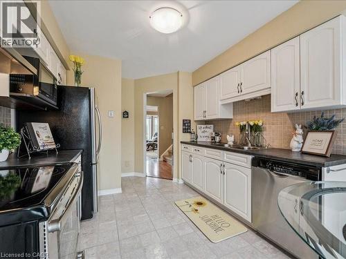 Kitchen featuring cream cabinetry, dark countertops, a stainless steel refrigerator, and a double basin sink - 245 Bishop Street S Unit# 4, Cambridge, ON - Indoor Photo Showing Kitchen