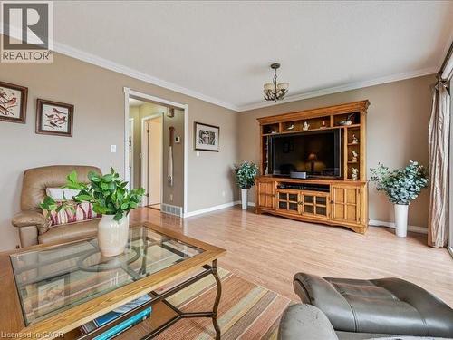 Living area featuring wood-finish flooring, a wood entertainment center with shelving, crown molding, and neutral wall tones - 245 Bishop Street S Unit# 4, Cambridge, ON - Indoor Photo Showing Living Room