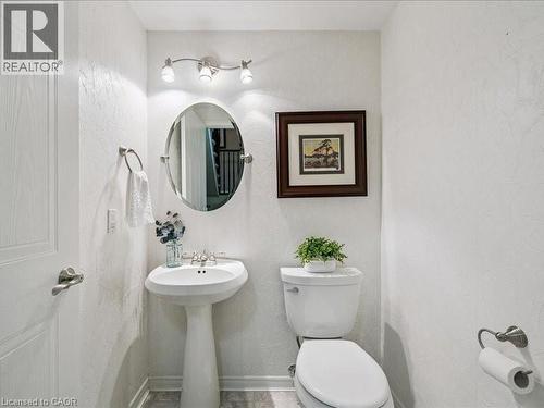 Pedestal sink with a brushed nickel faucet, oval wall mirror, and track lighting - 245 Bishop Street S Unit# 4, Cambridge, ON - Indoor Photo Showing Bathroom