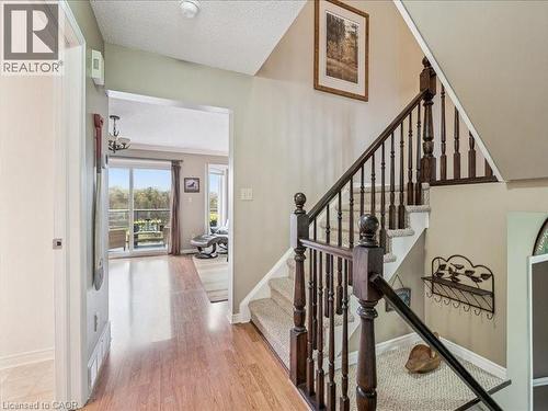 Entryway featuring wood-finish flooring, a carpeted staircase with dark wood banister, and an open doorway leading to a living area with a sliding glass door - 245 Bishop Street S Unit# 4, Cambridge, ON - Indoor Photo Showing Other Room