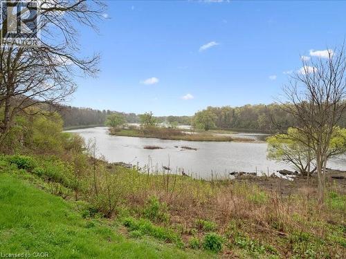 Expansive waterfront setting featuring a tranquil body of water, lush green bank, and established trees - 245 Bishop Street S Unit# 4, Cambridge, ON - Outdoor With View