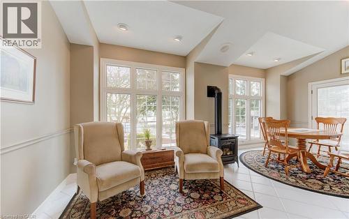 Bright sunroom featuring multiple large windows, a freestanding wood-burning stove, vaulted ceilings, and tile flooring - 514 Colonial Drive, Waterloo, ON - Indoor