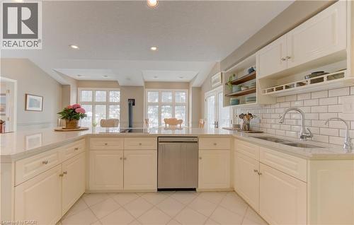 Bright kitchen featuring white cabinetry, light-toned countertops, a stainless steel dishwasher, and a subway tile backsplash - 514 Colonial Drive, Waterloo, ON - Indoor Photo Showing Kitchen With Double Sink