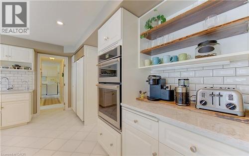 White shaker cabinetry, stainless steel double wall ovens, built-in refrigerator panel, light-toned countertop, and subway tile backsplash - 514 Colonial Drive, Waterloo, ON - Indoor Photo Showing Kitchen
